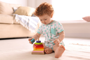 Cute little child playing with toy on floor at home