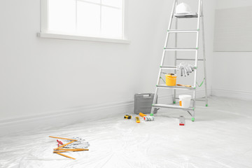 Stepladder and different tools near wall in room. Interior renovation