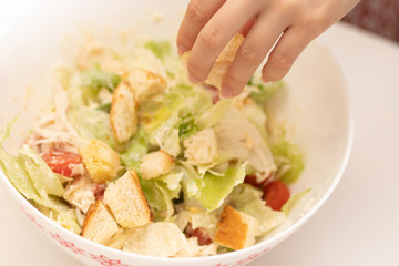 Cooking Salad. Female hands add croutons to salad