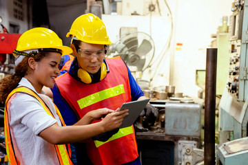 Engineer with Female mechanical worker with yellow safety helmet checking on production in a factory. Industrial, Mechanic, Engineering Concept.  