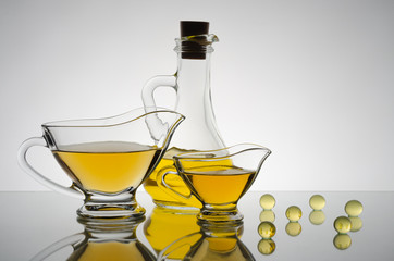 Large and small glass transparent saucers with yellow transparent sauce, behind a glass transparent oiler with yellow oil.
