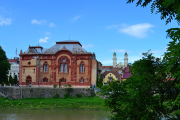 Fototapeta na wymiar building of the old synagogue on the banks of the river and the bell tower of the Holy Cross Cathedral, Uzhgorod, Ukraine