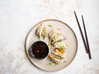 Chinese traditional dumplings - gyoza with pork and vegetables on a round plate with soy sauce in a...