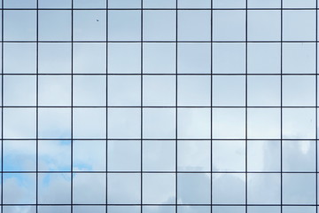 Glass with mirror effect in frames, facing of modern office building. Reflection of the sky in the glass facade of an office building