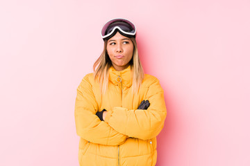 Young caucasian woman wearing a ski clothes in a pink background frowning face in displeasure, keeps arms folded.