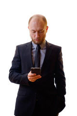 Businessman in a black suit, shirt and tie using a mobile phone in order to keep abreast of all the news. Makes the photo on the mobile phone, writes notes or new contacts and plays the game.