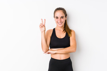 Young caucasian fitness woman posing in a white background showing number two with fingers.