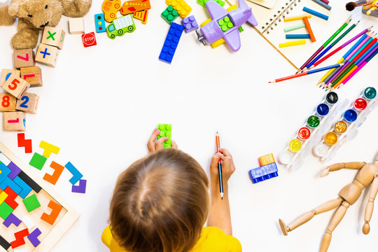 Prescool boy drawing on floor on paper. Kid play with blocks, plane and cars.