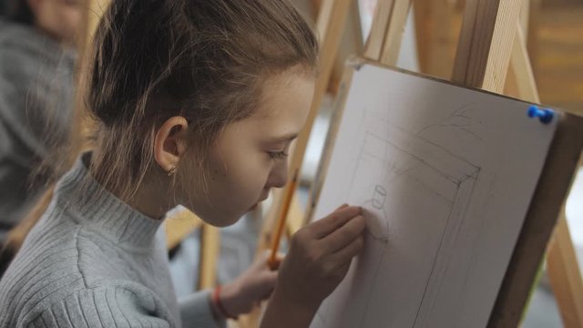 The girl in the drawing school learn to draw still life. Close-up of girl making sketches with a pencil on a sheet of paper.