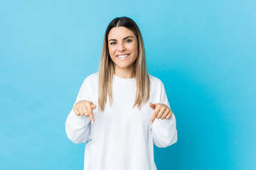 Fototapeta premium Young caucasian woman isolated points down with fingers, positive feeling.