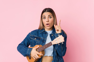 Young caucasian woman playing ukelele having some great idea, concept of creativity.