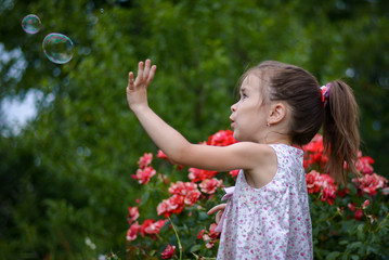 girl in flowers plays with soap bubbles