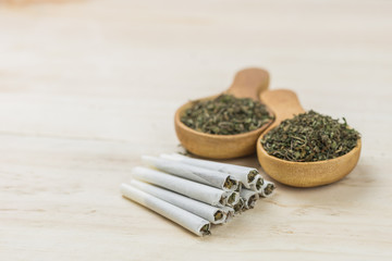 Cannabis joints with cannabis in wooden spoon on wooden background.