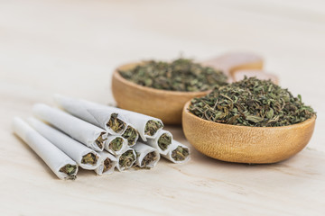 Cannabis joints with cannabis in wooden spoon on wooden background.