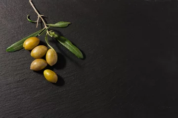 Fototapeten Olives and an olive branch with leaves on black background for copy space. © Caterina Trimarchi