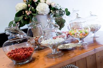 Table with glass jars with assortment of colored sugared almonds