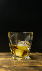 Glass of whiskey on wooden background close up