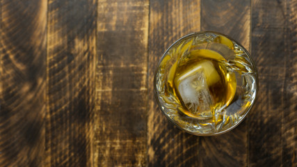 Glass of whiskey on wooden background close up