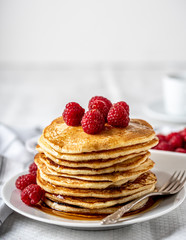 Sweet homemade pancakes with raspberries and blueberries on white plate.