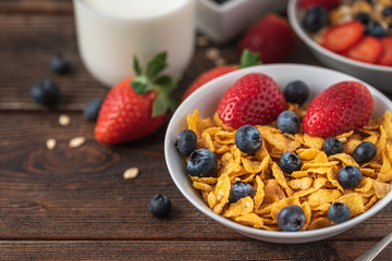 hips with blueberries and raspberries in white bowl in dark wooden desk.