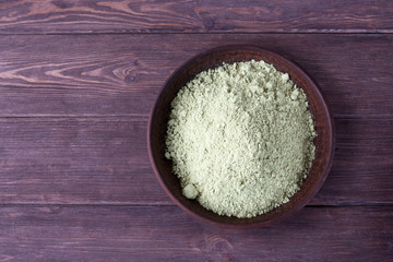 Pumpkin seed flour in a clay plate on a dark wooden background.