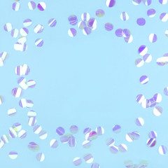 Pearl confetti on blue background. Flat lay, top view.