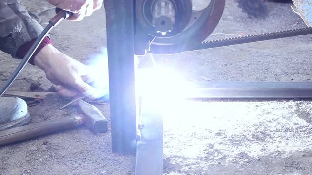 Electroplating of metal structures. The worker welds metal and a metal rod to secure them. Sparks and flash from electric welding.