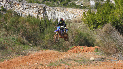 Zoom photo of unidentified motocross rider performing extreme stunts in off road dirt track