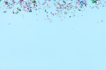 Fototapeta na wymiar Multicolored confetti on blue background. Flat lay, top view.