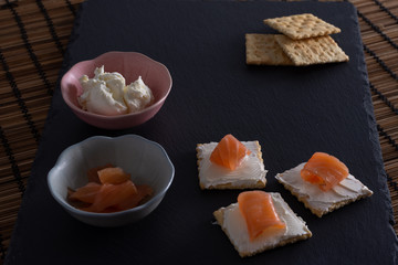 Snack en pizarra con salmón en galleta con queso