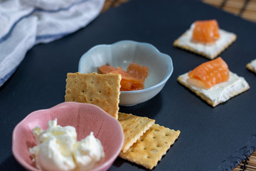 Snack en pizarra con salmón en galleta con queso