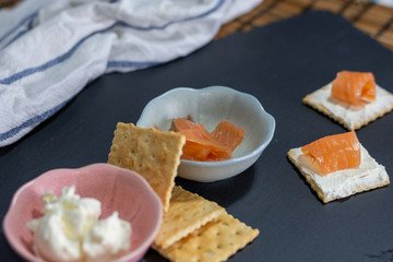 Snack en pizarra con salmón en galleta con queso