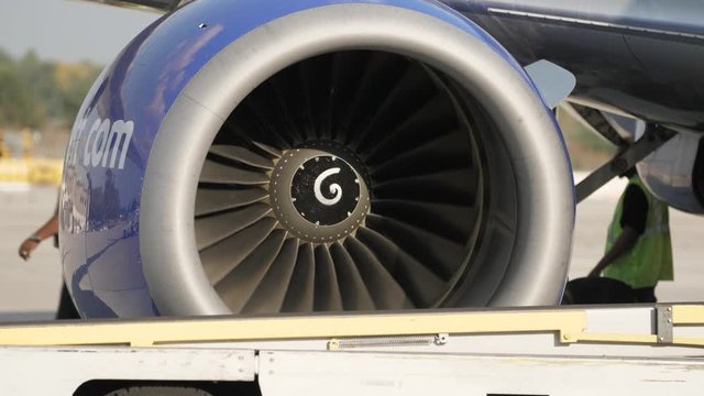 Commercial Airplane Jet Turbine Engine Spins With Workers In Background