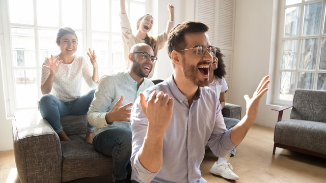 Excited multicultural friends watching on tv sport game feels euphoric