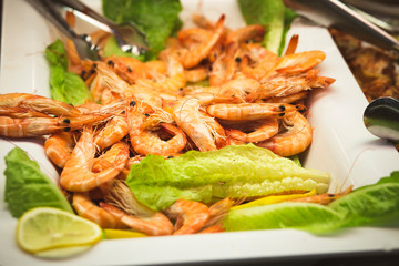 cooked prawns on white plate with lettuce and lemon slices