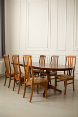 A classic set of wooden furniture for the kitchen. A set of chairs to the table in a classic interior