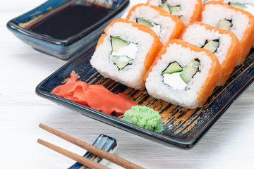 Sushi roll Philadelphia on the plate over white wooden table background.