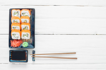 Sushi roll Philadelphia on the plate over white wooden table background.