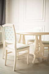 White tables and chairs for dinner in a classic interior. Upholstered chairs for comfortable sitting at the table