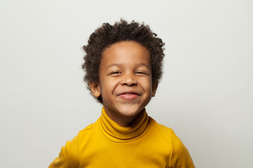 Funny happy little black kid boy laughing on white background
