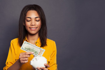 Pretty black girl putting in money box 100 dollars banknote