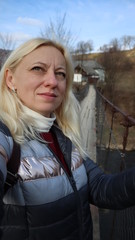 young fashionable stylish woman blonde in a good mood stands on a suspension bridge