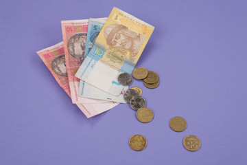 Close up photo of small ukrainian money with metal coins isolated purple background