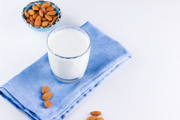 Almond milk with almond on white background. Organic almond milk in a glass for healthy breakfast. Vegan milk from almonds nuts on a blue napkin. Alternative milk