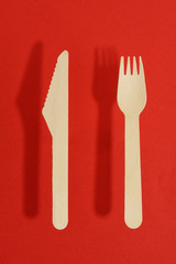 disposable wooden fork and knife on a red background