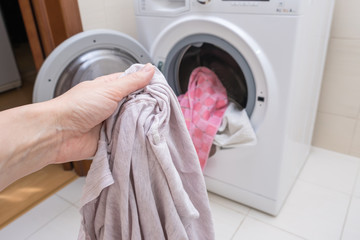 Woman housewife pull the laundry out of or load a washing machine