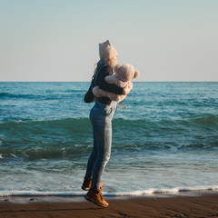 Girl on the beach plays with a teddy bear