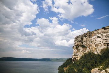 Beautiful stone cliff and big lake. Old stone caves, green hill and river landscape. Bakota lake and Dnister river in Ukraine.Travelling and exploring national park. Summer vacation