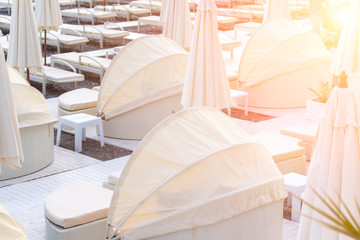 Fototapeta na wymiar Luxury beach near the sea with sun beds and umbrellas in pastel colors in summer