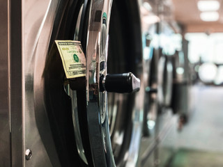 Closeup of cash money sticking out of a washing machine at a laundromat.